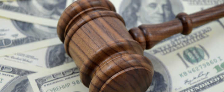 An image focused on the legal side of monetary gains using a gavel and an abundance of American cash as a background.