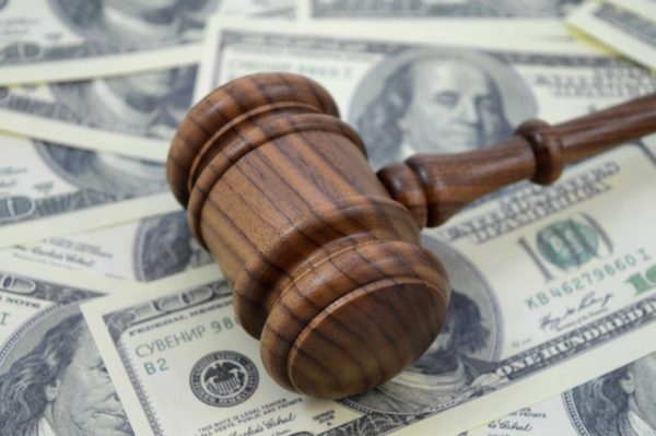 An image focused on the legal side of monetary gains using a gavel and an abundance of American cash as a background.