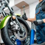 Mechanic in overalls repairing sports motorcycle at the workshop indoors