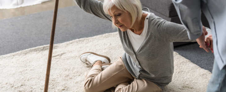 cropped view of man helping sick senior mother with cane fallen on floor