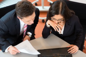 man and woman attorneys viewing papers and computer