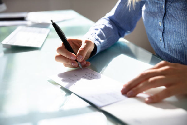 woman writing a pay check for lost wages after a car accident