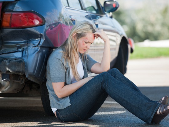 woman sitting outside her car after an accident