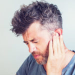 man grimacing with ear pain