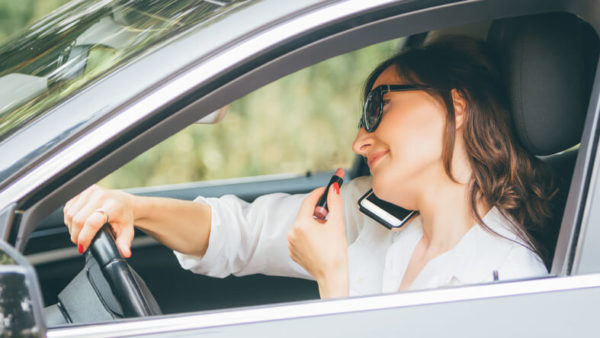 distracted driver talking on the phone and putting on lipstick