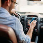 man-looking-at-mobile-phone-while-driving