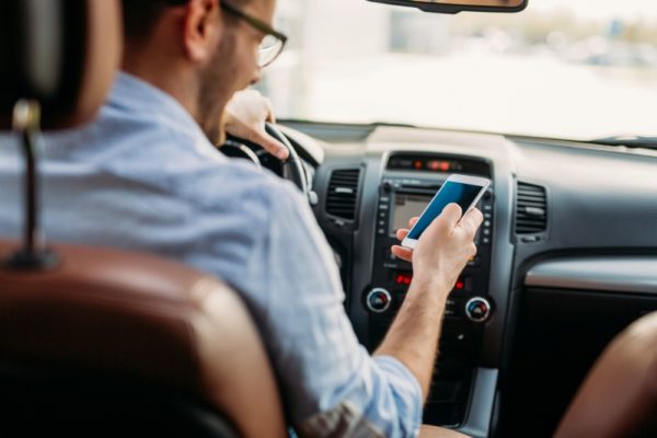 man-looking-at-mobile-phone-while-driving