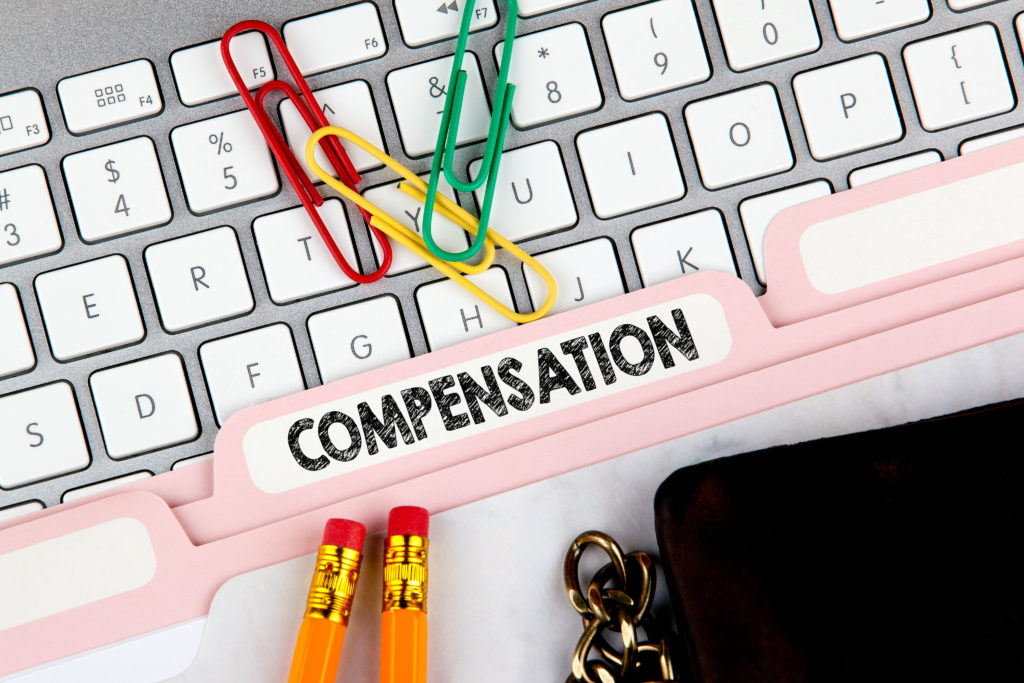 Compensation concept. Folder Register on Background of Computer Keyboard