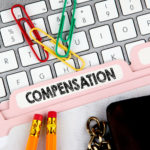 Compensation concept. Folder Register on Background of Computer Keyboard