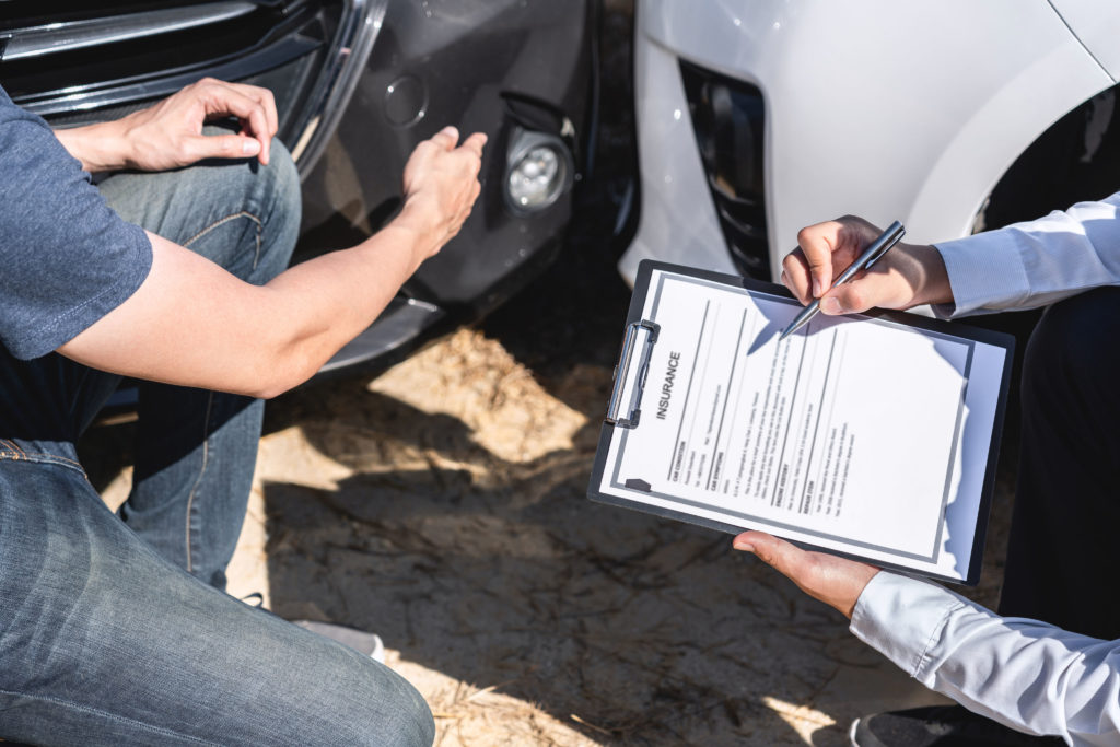 Insurance Agent examining car crash and customer assessed negotiation, checking and signing on report claim form process after accident collision, Accident and insurance concept.