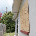 A home with plywood covering the window in preparation for a hurricane. The storm clouds are gathering in the sky. Horizontal view.