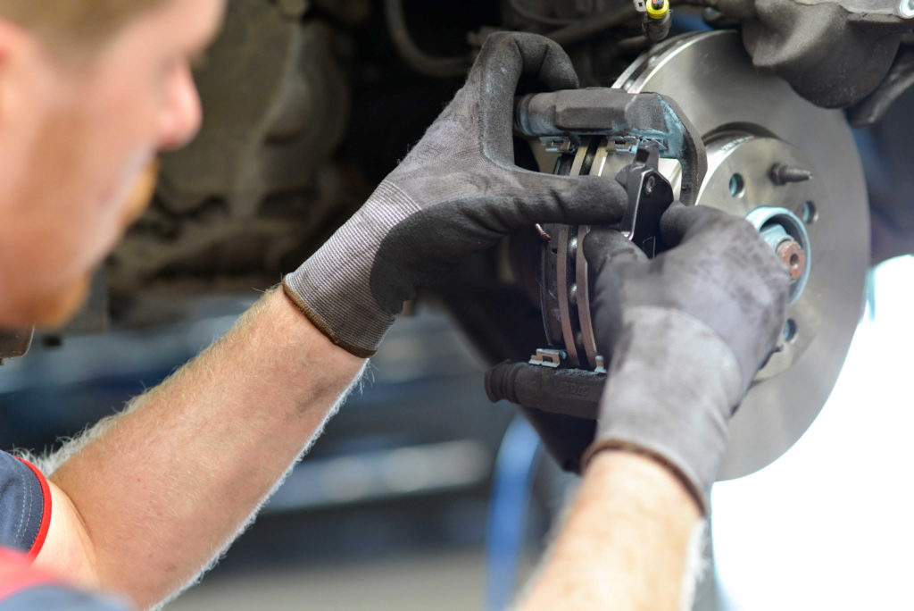 car mechanic repairs breakes from vehicle in a workshop