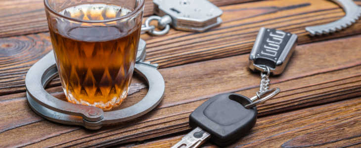 Concept drunkenness driving. Handcuffs, a glass of alcohol, car keys.