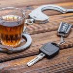 Concept drunkenness driving. Handcuffs, a glass of alcohol, car keys.