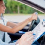Instructor of driving school giving exam while sitting in car
