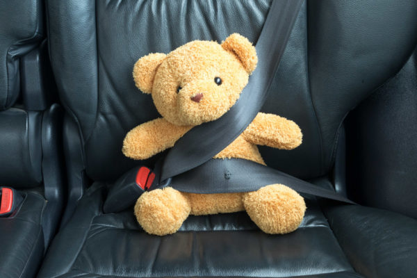 Teddy bear fastened in the back seat of a car