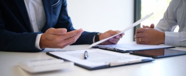 personal injury lawyer discusses cases with a client while looking at documents.
