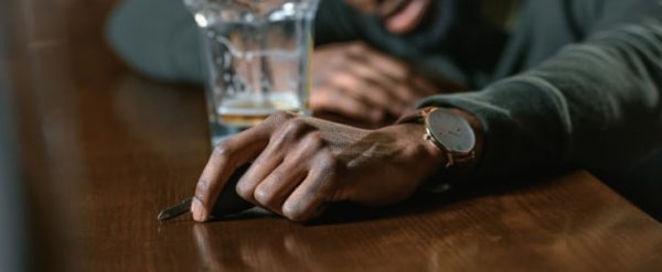 man at bar sleeping with car keys in his hand and a beer near his other hand.