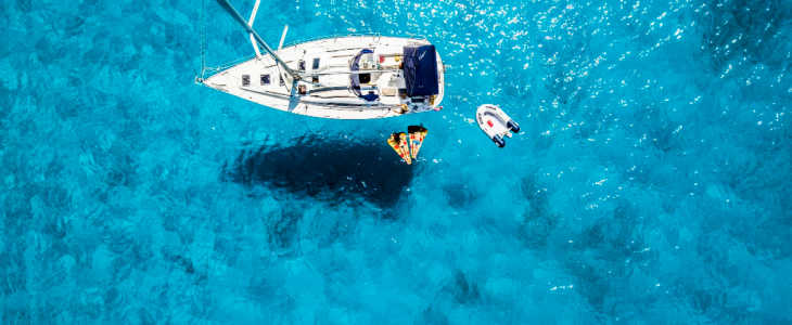 boat in the water with 2 people clear blue ocean shot from above