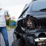 Unhappy Female Driver With Damaged Car After Accident Calling Insurance Company On Mobile Phone