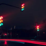 traffic lights at night with lots of traffic zooming past.