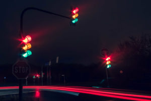 traffic lights at night with lots of traffic zooming past.