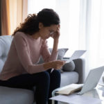 woman reading medical bills by laptop