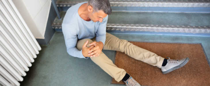 Older man slip and fall on a stair case holding his knee
