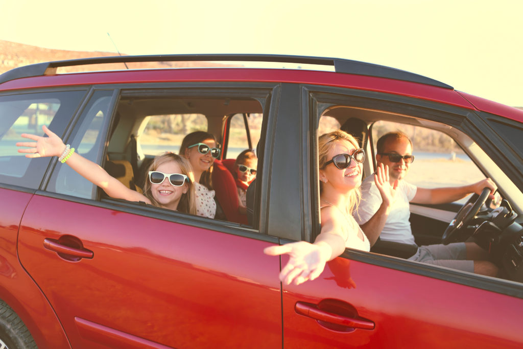 Family in the car on vacation, smiling and looking happy and excited