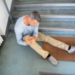 Older man slip and fall on a stair case holding his knee