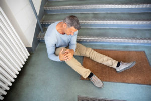 Older man slip and fall on a stair case holding his knee
