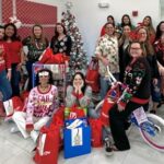 Steinger Greene and Feiner Employees in front of Christmas Tree and Gifts for Children in need