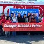 Steinger, Greene and Feiner employees standing in front of a One Blood red bus after a blood drive to donate blood to people in need in our communities.