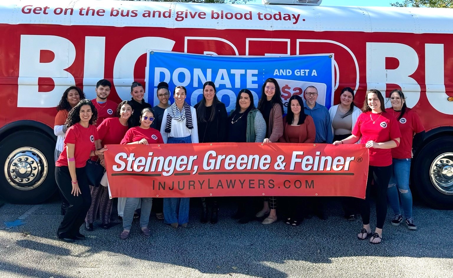 Steinger, Greene and Feiner employees in front of a One Blood Red Bus after blood drive donation for the community